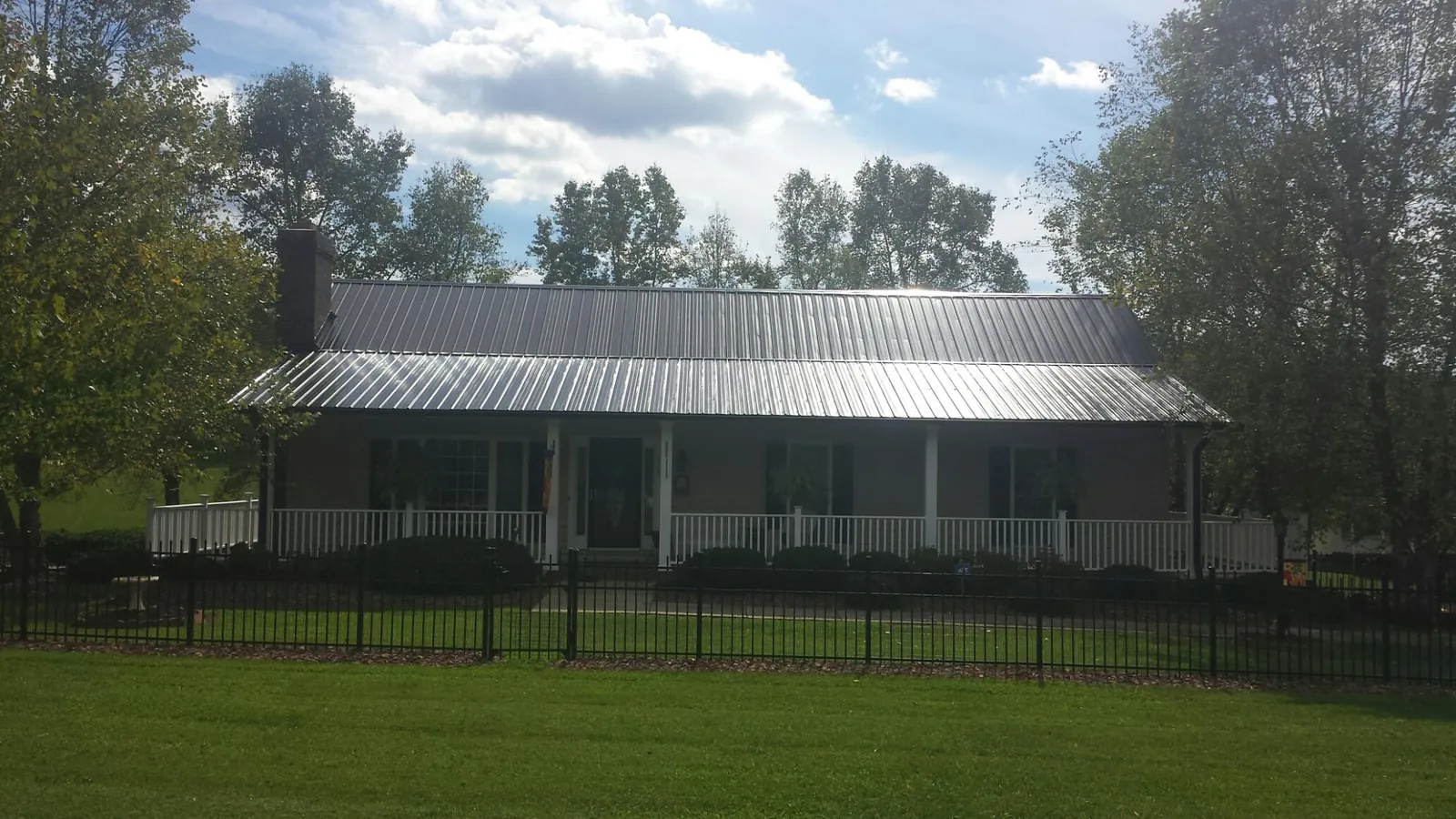 Gray metal roof on a brick ranch with a full width front porch — Gutter Guard Installation work by our crew in Arlington